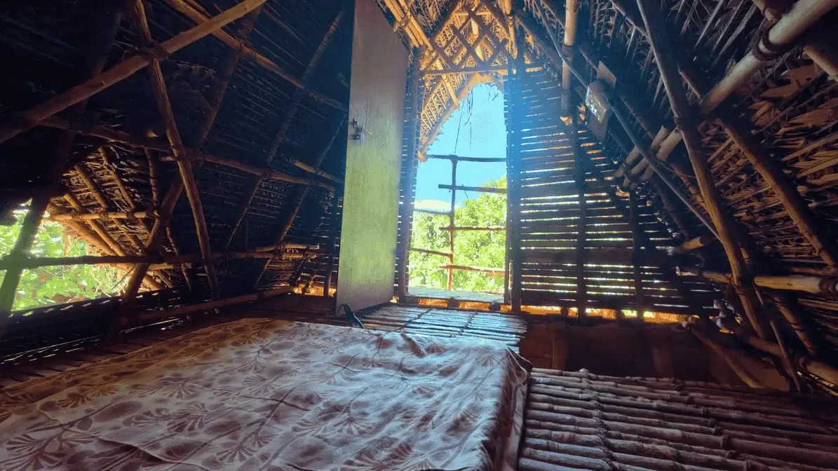 Interior view of a hut showing bed and a balcony